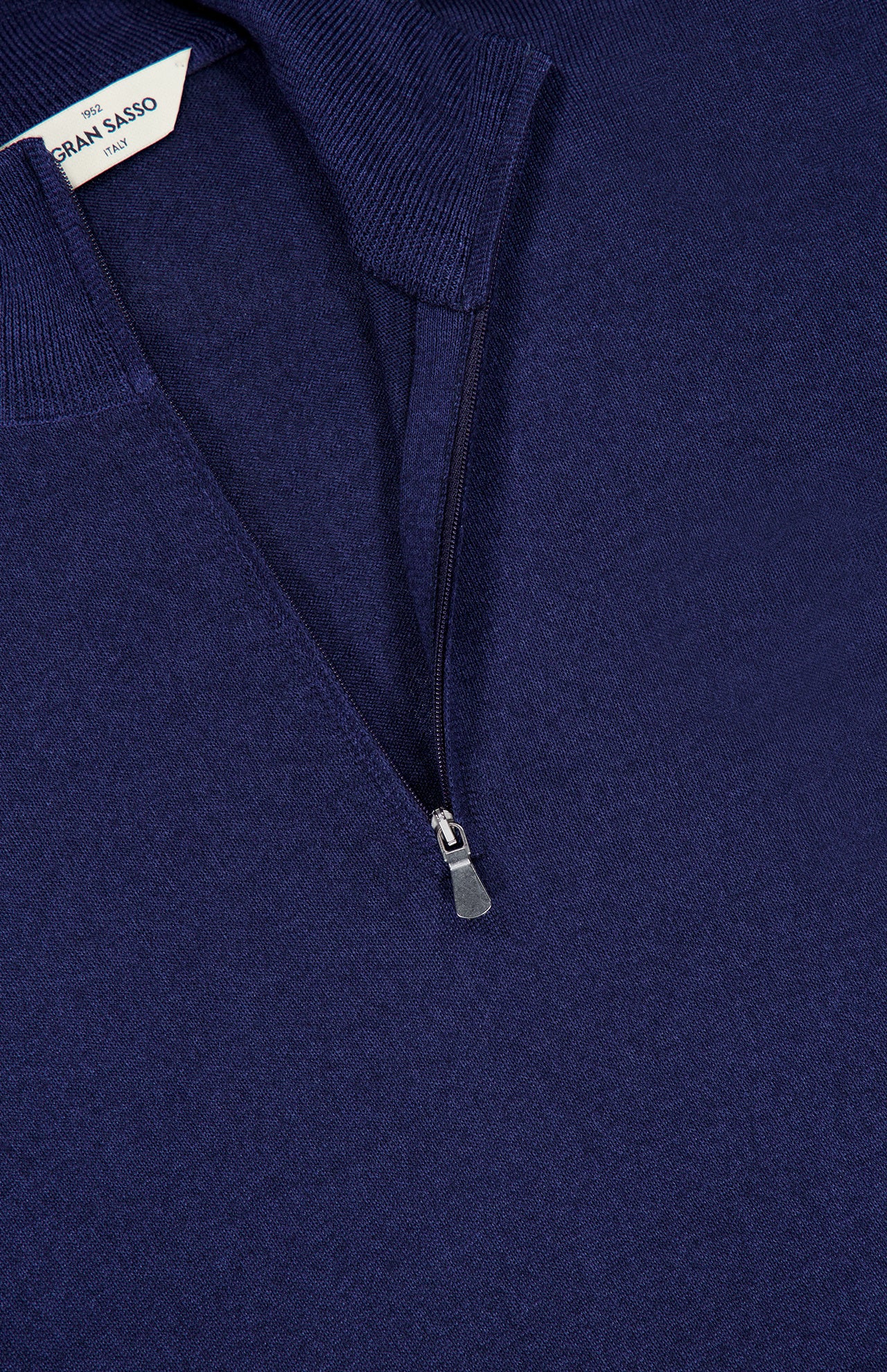 Close-up of the GRAN SASSO Quarter Zip Wool Sweater in dark blue, featuring a partially unzipped collar. A white tag inside the collar displays text indicating that this pure wool sweater is made in Italy.