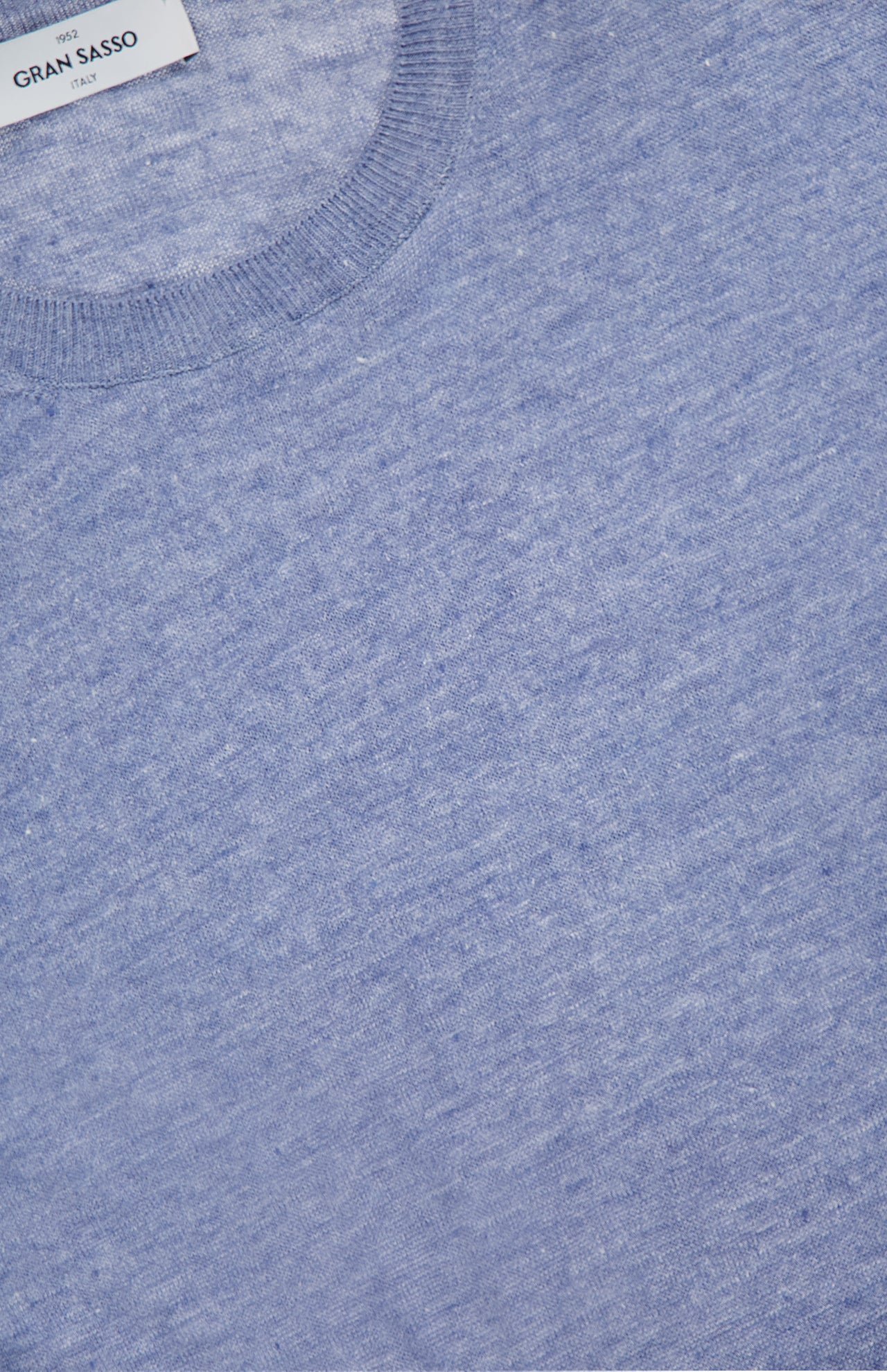 Close-up of a light blue GRAN SASSO Short Sleeve Crewneck Top featuring a ribbed neckline and a white GRAN SASSO ITALY label at the top, showcasing Italian craftsmanship.