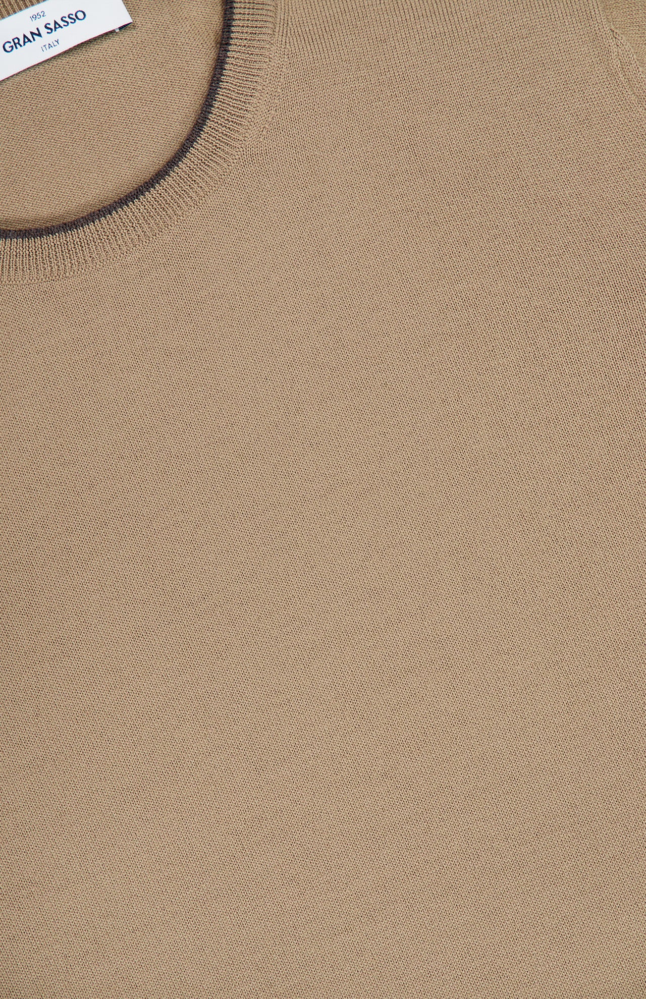 Close-up of the Suede Elbow Patch Crewneck Sweater by GRAN SASSO, featuring a tan knit made from soft virgin wool and a round neckline. A small white clothing label is visible at the top left corner.