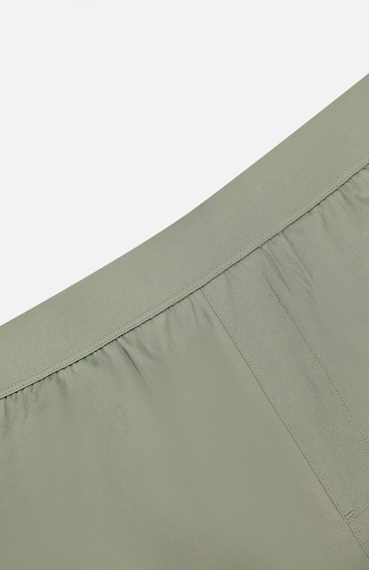 Close-up of the waistband and upper section of GREYSON Arenac Perforated Sport Short in light green, featuring an elasticized back, smooth front, detailed stitching, and a zip pocket—ideal for those seeking breathable performance.