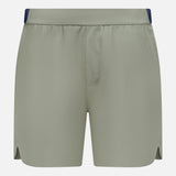 The GREYSON Arenac Perforated Sport Short features a light sage green color, elastic waistband, small side slits, and a zip pocket. These breathable athletic shorts have no visible branding and are shown on a white background.