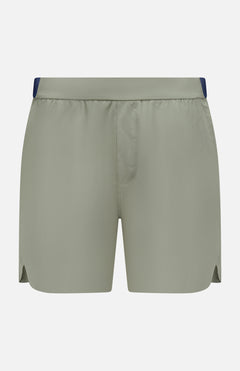 The GREYSON Arenac Perforated Sport Short features a light sage green color, elastic waistband, small side slits, and a zip pocket. These breathable athletic shorts have no visible branding and are shown on a white background.