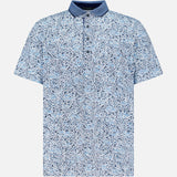 The GREYSON Buffalo Soldier Polo Shirt features a light blue, short-sleeved design with a navy collar and abstract blue and white speckled pattern. It offers a relaxed fit, button placket, moisture-wicking fabric, and built-in UV protection.