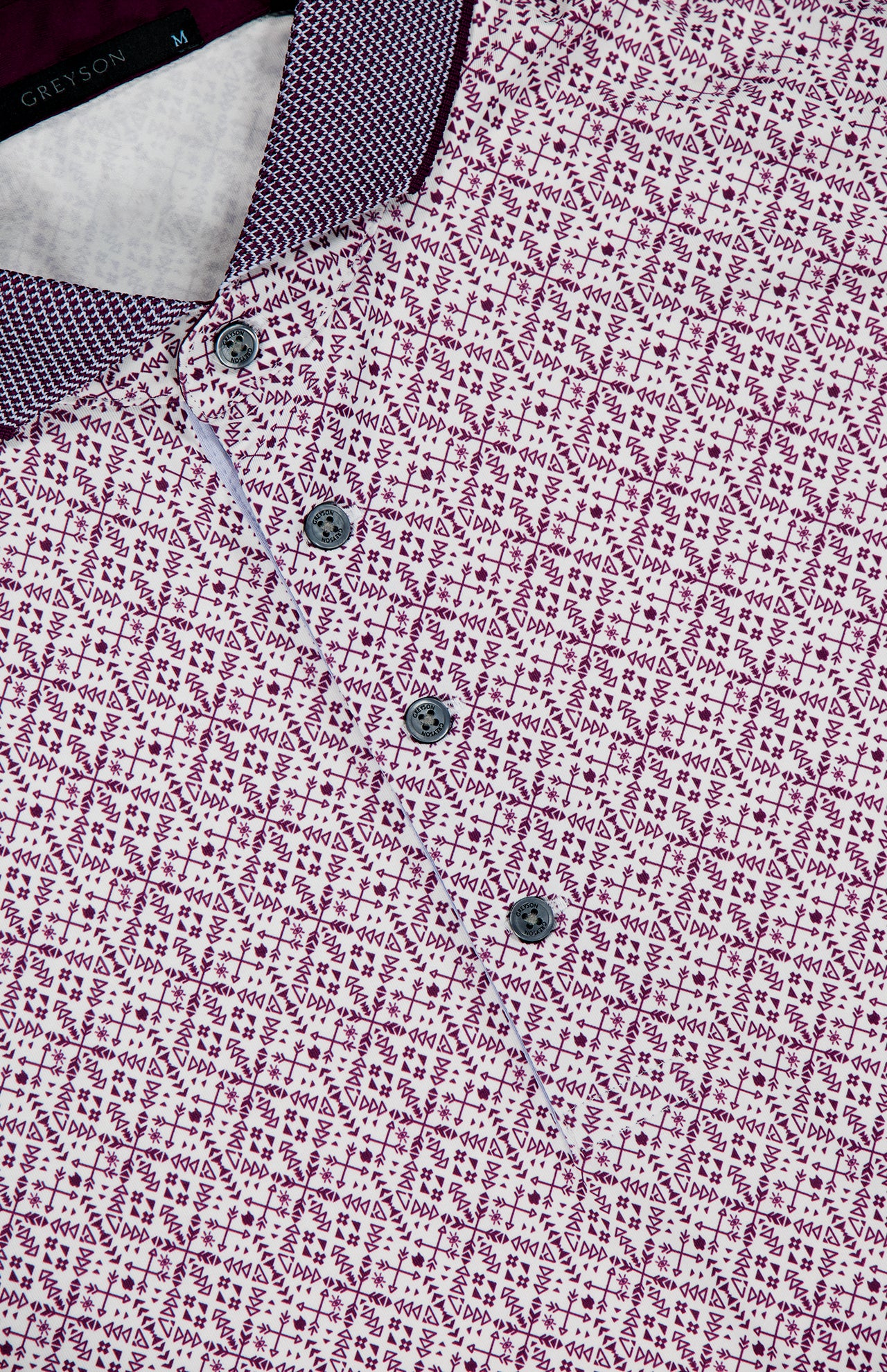 A close-up of the GREYSON Echo Falls Polo Shirt, showcasing a purple and white geometric pattern, four dark buttons, a textured contrast collar, and moisture-wicking fabric for all-day comfort.