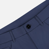Close-up of the Montauk 5 Pocket Pant by GREYSON in blue, crafted from premium Italian fabric, highlighting the waistband, black button, belt loops, and part of a front pocket against a light gray background.
