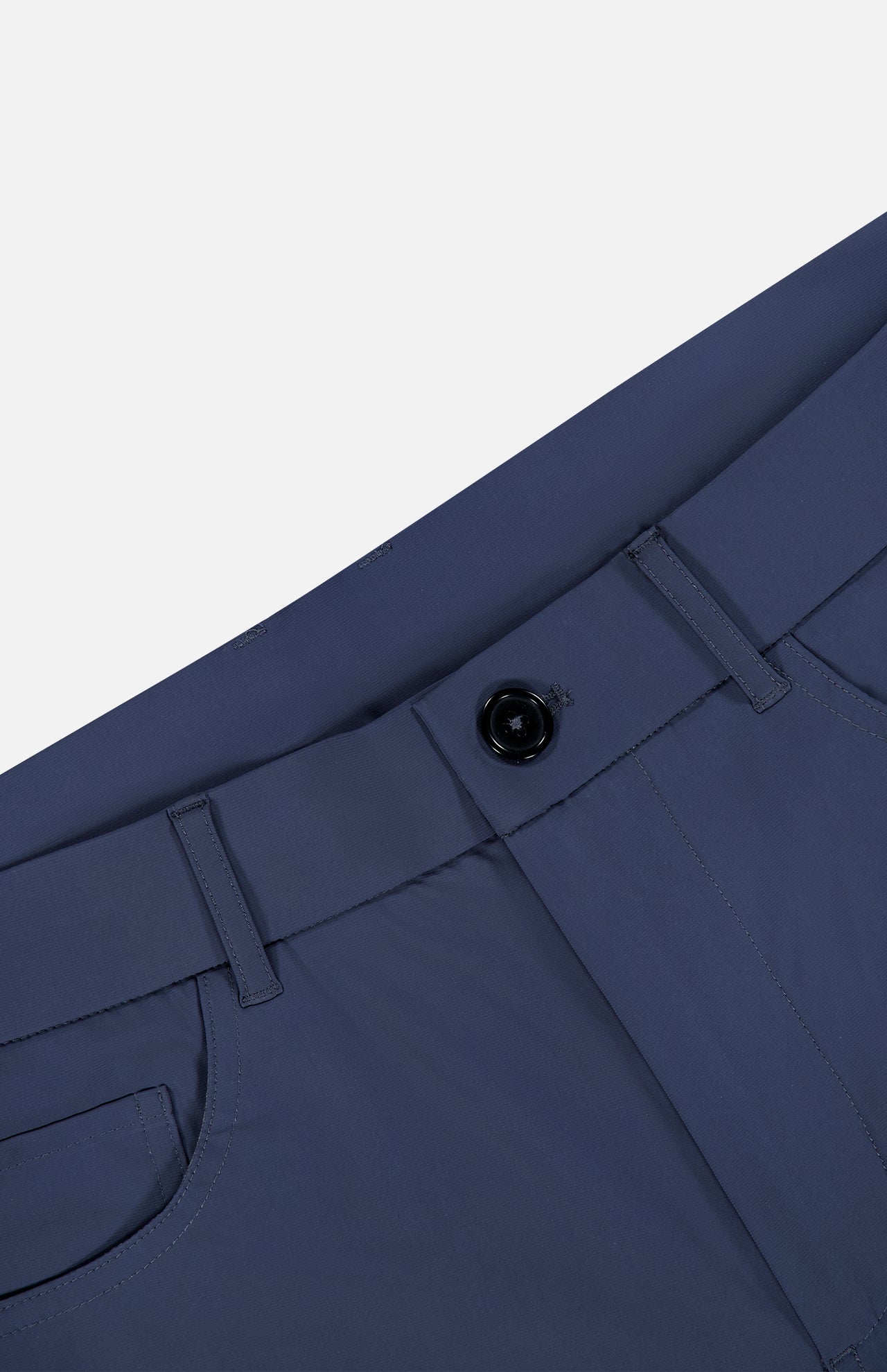 Close-up of the Montauk 5 Pocket Pant by GREYSON in blue, crafted from premium Italian fabric, highlighting the waistband, black button, belt loops, and part of a front pocket against a light gray background.