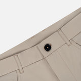 The Montauk 5 Pocket Pant by GREYSON is displayed diagonally, showcasing a black button, visible belt loops, pockets, and detailed stitching. Expertly crafted from premium Italian fabric with a smooth finish, these beige trousers offer an elegant contrast against the plain white background.