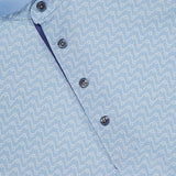 Close-up of the Rogue River Polo Shirt by GREYSON, a light blue performance polo with a white abstract squiggle pattern, four dark buttons, and a collar trimmed in white. Moisture-wicking fabric and subtle branding inside the collar combine comfort and style.
