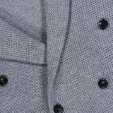 Close-up of the textured gray fabric in a woven pattern, complete with six black buttons arranged in a double-breasted style—ideal for smart-casual ensembles, the GREYSON Saratoga Double Breasted Blazer Cardigan showcases modern sophistication.