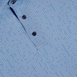 Close-up of the Silent Pact Polo Shirt by GREYSON, featuring a light blue hue, white dotted pattern, three metallic placket buttons, and built-in moisture wicking for added comfort.