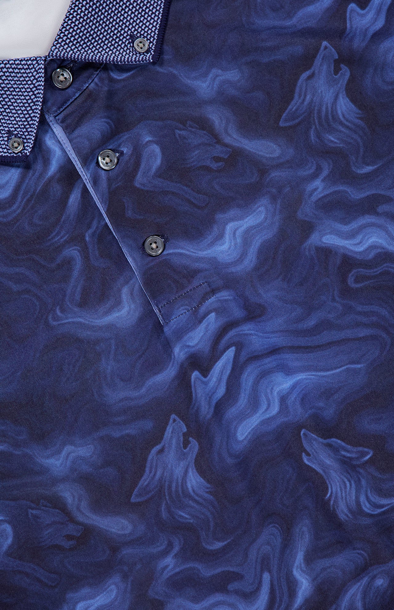 Close-up of the GREYSON Smoke In The Den Polo Shirt in blue, featuring a swirling marbled pattern and three-button placket. The collar stands out with a contrasting geometric design in light blue and white. This performance polo also provides UV protection for enhanced comfort during outdoor activities.