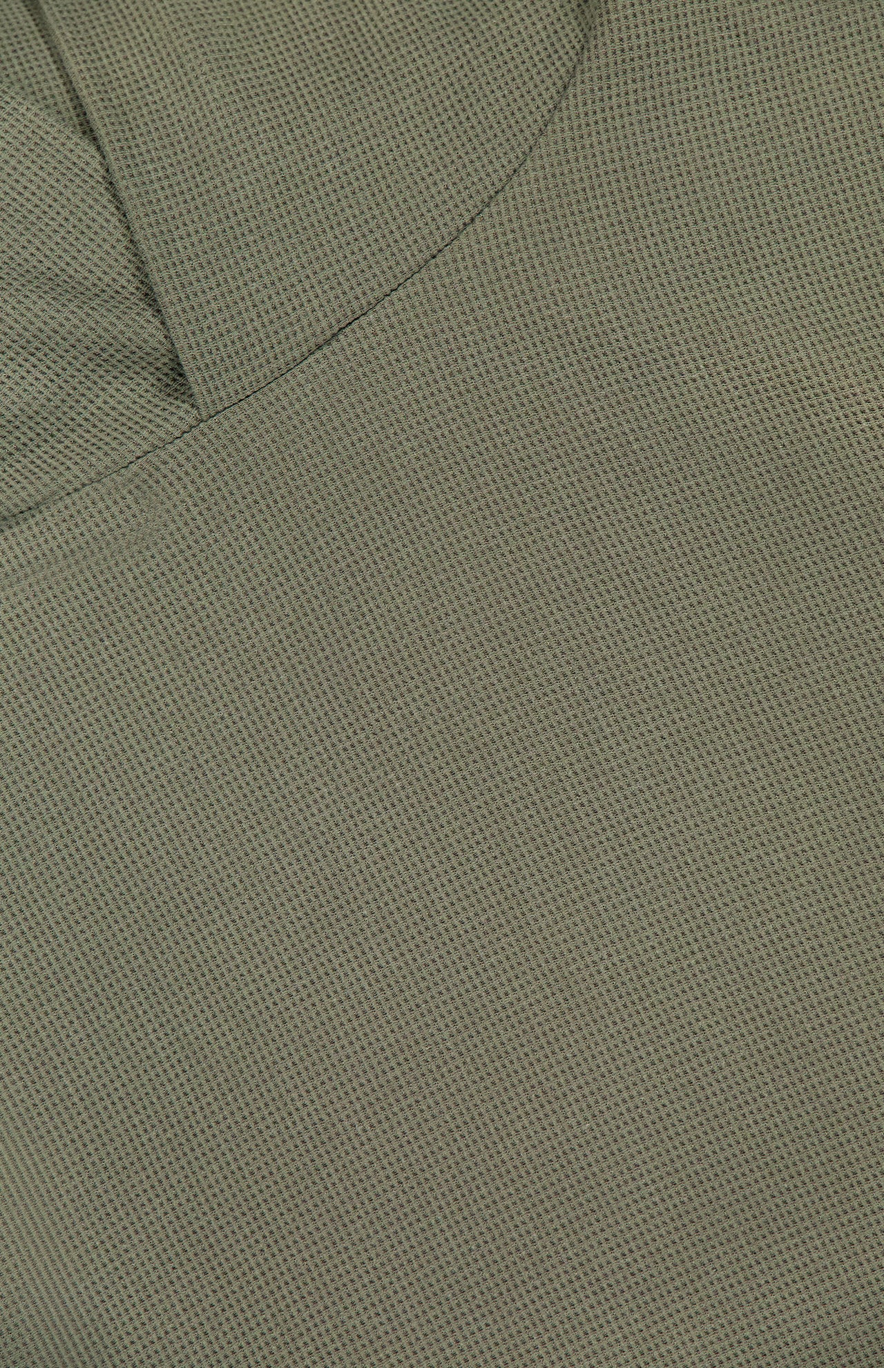 Close-up of the olive green textured fabric from the GREYSON Traverse Waffle Hoodie Sweatshirt, highlighting a visible seam and an overlapping fold in the upper left corner.