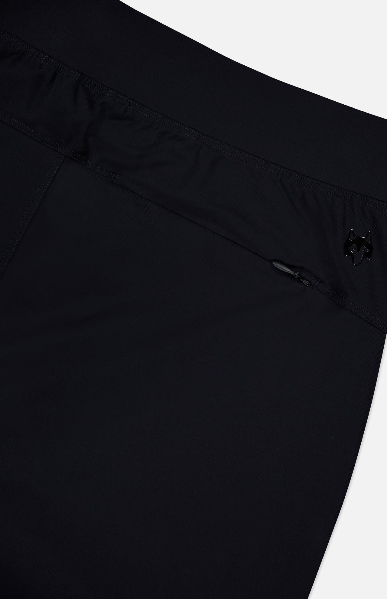 Close-up of the GREYSON Phoenix Jogger in black, showcasing a lightweight waistband with a small zipper pocket and an embroidered wolf’s head logo. The smooth, slightly shiny fabric adds to its sleek look.