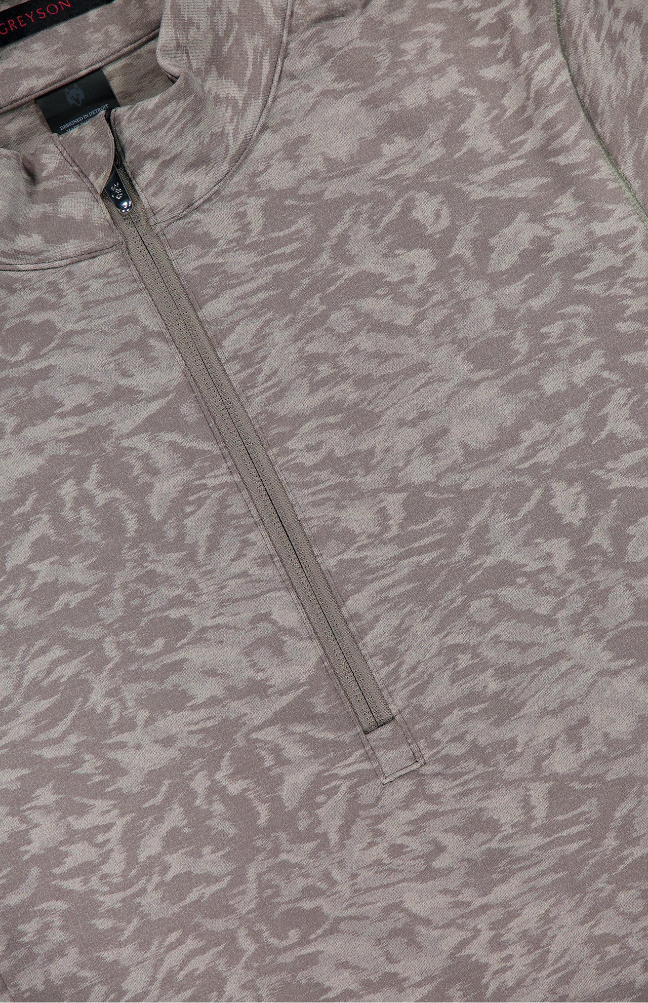 A close-up of the GREYSON Midas Wolf Jacquard Halley II Quarter Zip pullover in light brown and beige, featuring a subtle abstract pattern and a partially unzipped collar.