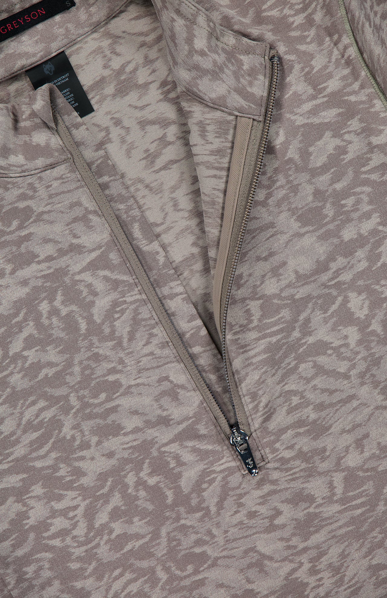 A close-up of the GREYSON Midas Wolf Jacquard Halley II Quarter Zip in light brown and beige jacquard, showcasing the partially unzipped quarter-zip neckline, visible inner lining, and brand tag near the collar.
