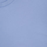 A close-up of the Ojai Cropped Crewneck Sweatshirt by GREYSON in light blue highlights the soft cotton-blend fabric, crew neck collar, shoulder seam, and a small section of its black tag with red text.