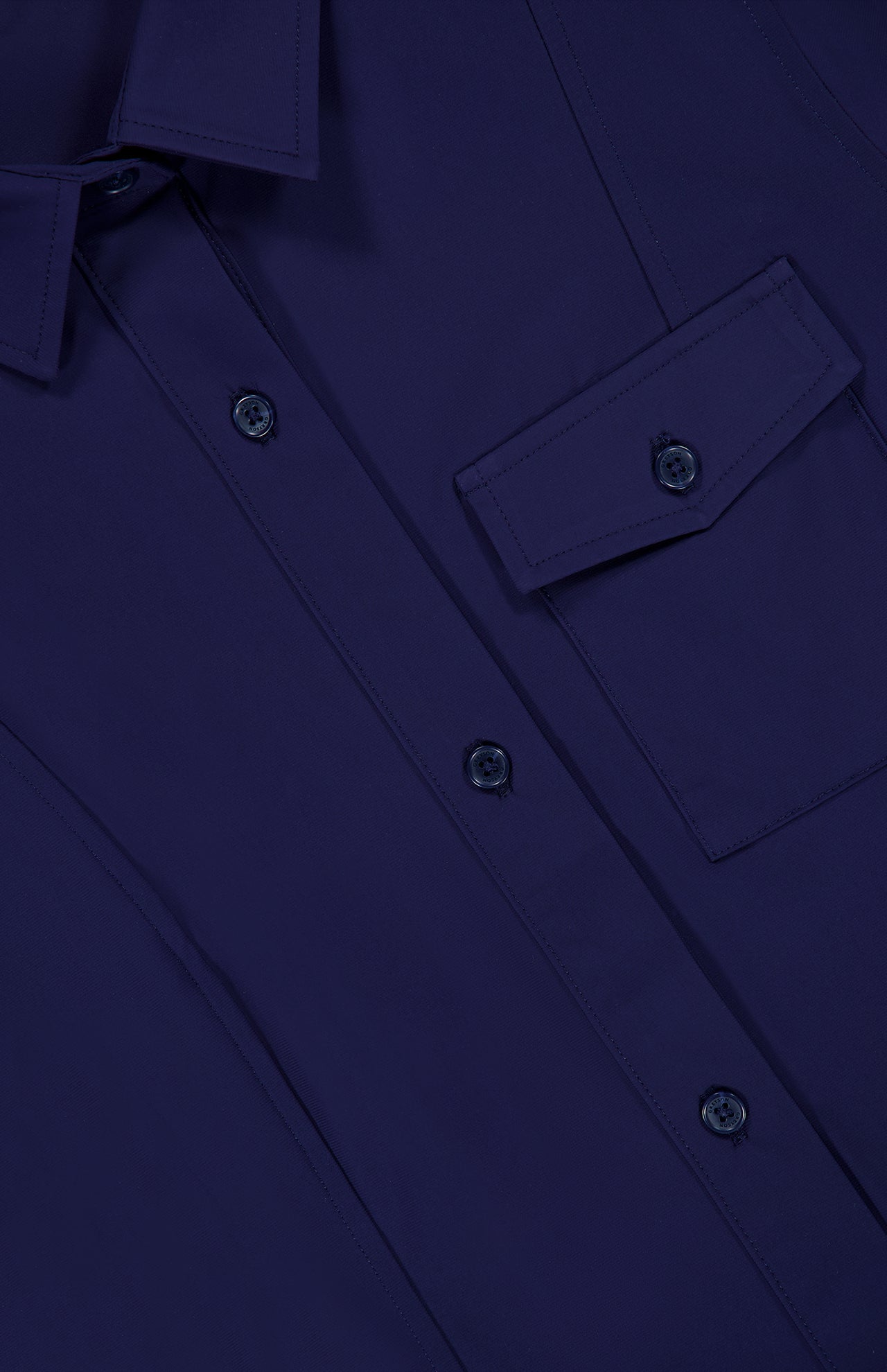 Close-up of the GREYSON Phoenix Belted Shirt Dress in navy blue, crafted from premium Italian stretch fabric, featuring a chest pocket with a flap and several matching blue buttons.