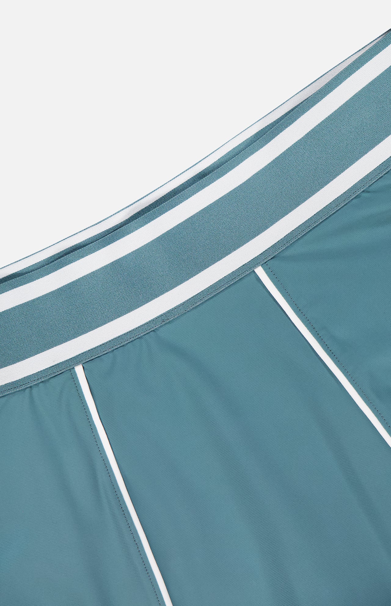 Close-up of the GREYSON Phoenix Flare Mini Skirt in teal-blue, featuring white piping and a wide striped elastic waistband. Its smooth, sporty fabric is ideal for layering over quick-drying boy shorts.