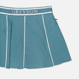 The GREYSON Phoenix Flare Mini Skirt is a teal athletic mini skirt with white piping, a bold GREYSON waistband, and quick-drying boy short lining for comfort.