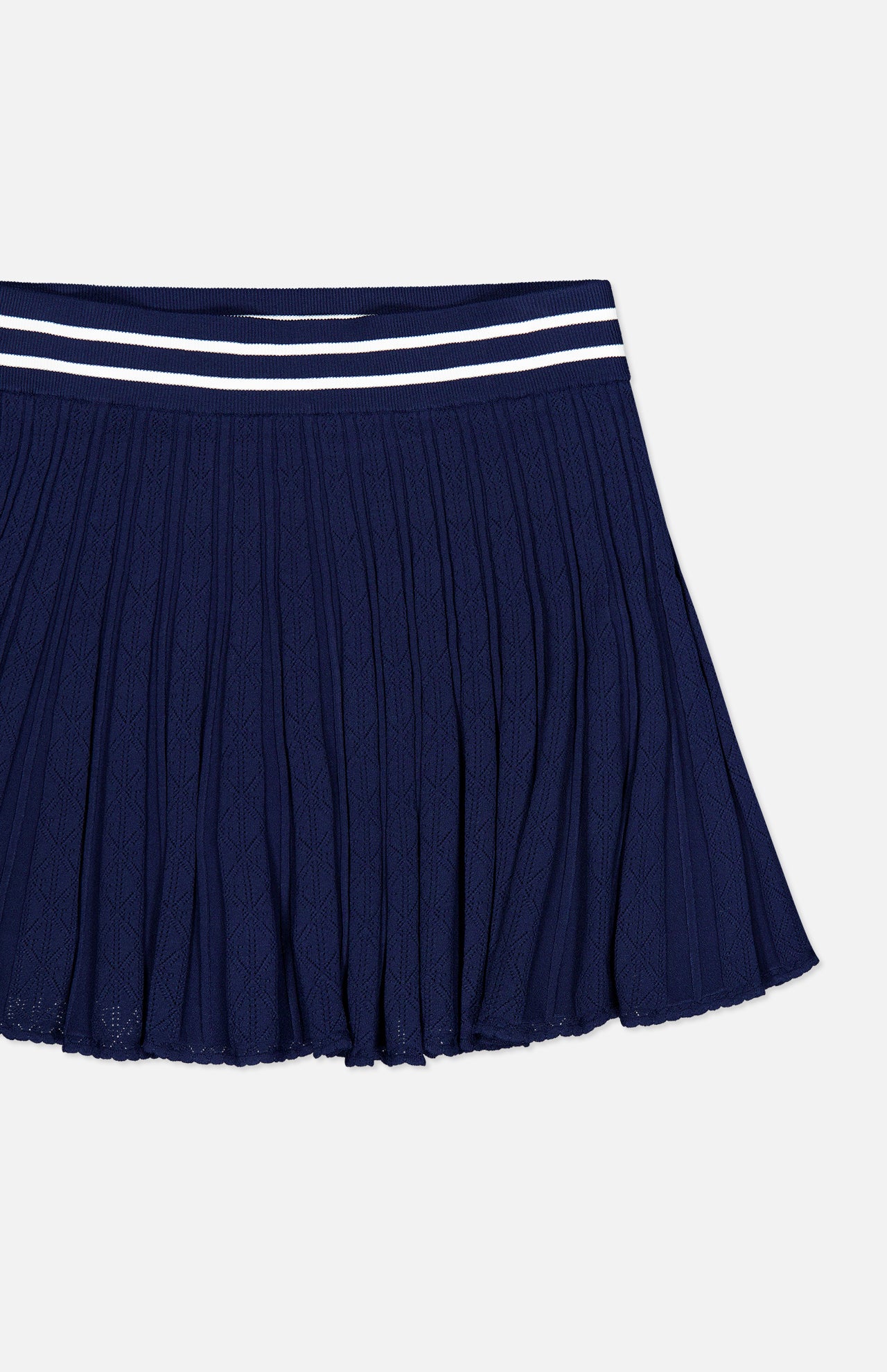 GREYSON Pointelle Mini Skirt in navy blue, featuring quick-dry fabric, a textured pattern, and a navy waistband accented with two parallel white stripes at the top. The skirt is shown laid flat on a white background.