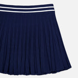 The GREYSON Pointelle Mini Skirt is a navy blue pleated skirt featuring a textured pointelle pattern and a waistband with two white horizontal stripes, designed with a built-in undershort for added comfort, shown against a white background.
