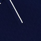 Close-up of the GREYSON Pointelle Sleeveless Polo Top in dark blue, showcasing its textured geometric knit, white-trimmed collar, and a glimpse of the two-button placket. The technical pointelle fabric lends depth and sophistication to this modern sleeveless classic.