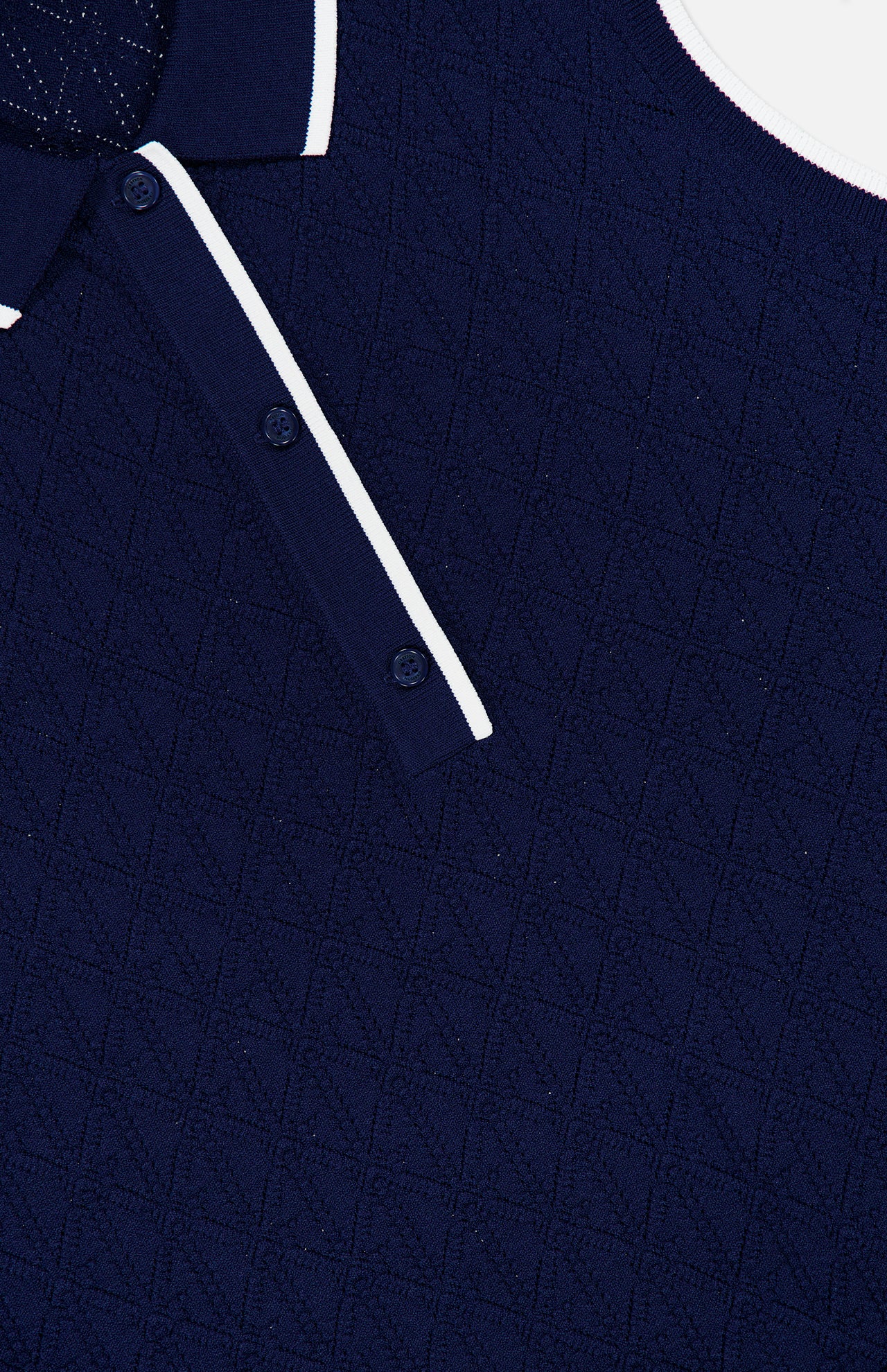 Close-up of the GREYSON Pointelle Sleeveless Polo Top in dark blue, showcasing its textured geometric knit, white-trimmed collar, and a glimpse of the two-button placket. The technical pointelle fabric lends depth and sophistication to this modern sleeveless classic.
