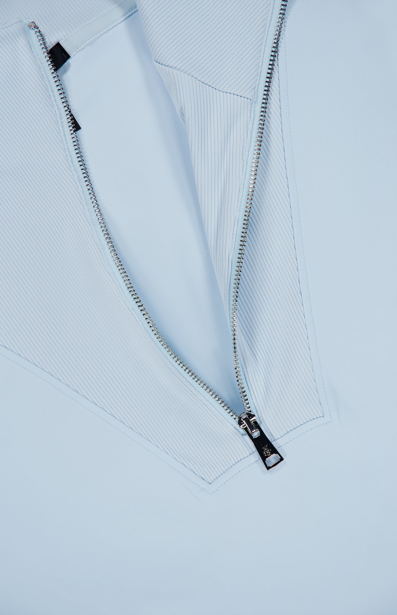 Close-up of a silver zipper partially unzipped on the GREYSON Soleil 1/2 Zip Pullover Sweater in light blue, revealing an Italian double-faced white and blue pinstriped fabric underneath.