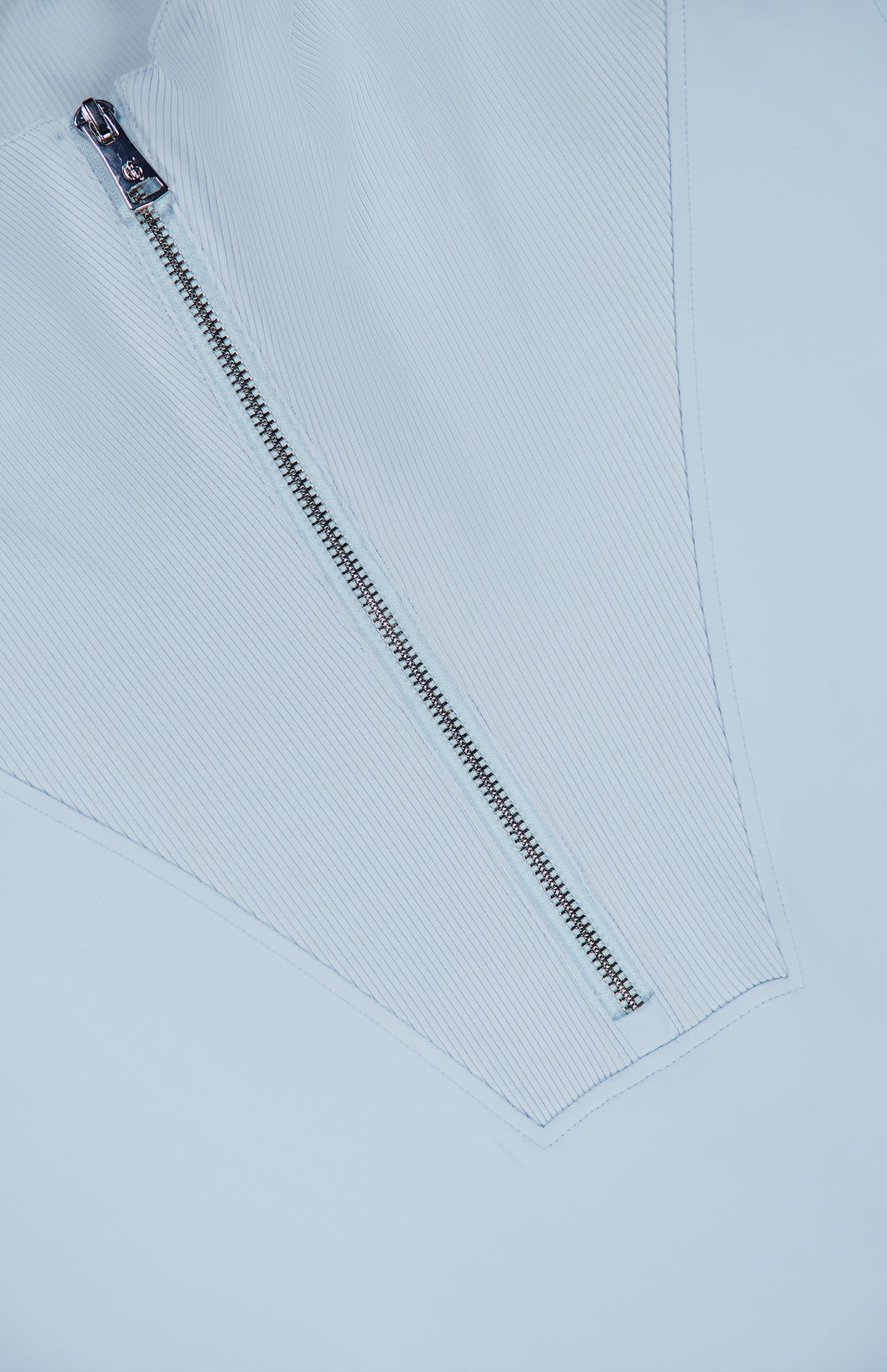 Close-up of the silver zipper on the GREYSON Soleil 1/2 Zip Pullover Sweater, crafted from light blue, ribbed Italian double-faced fabric and sewn into a V-shaped design.