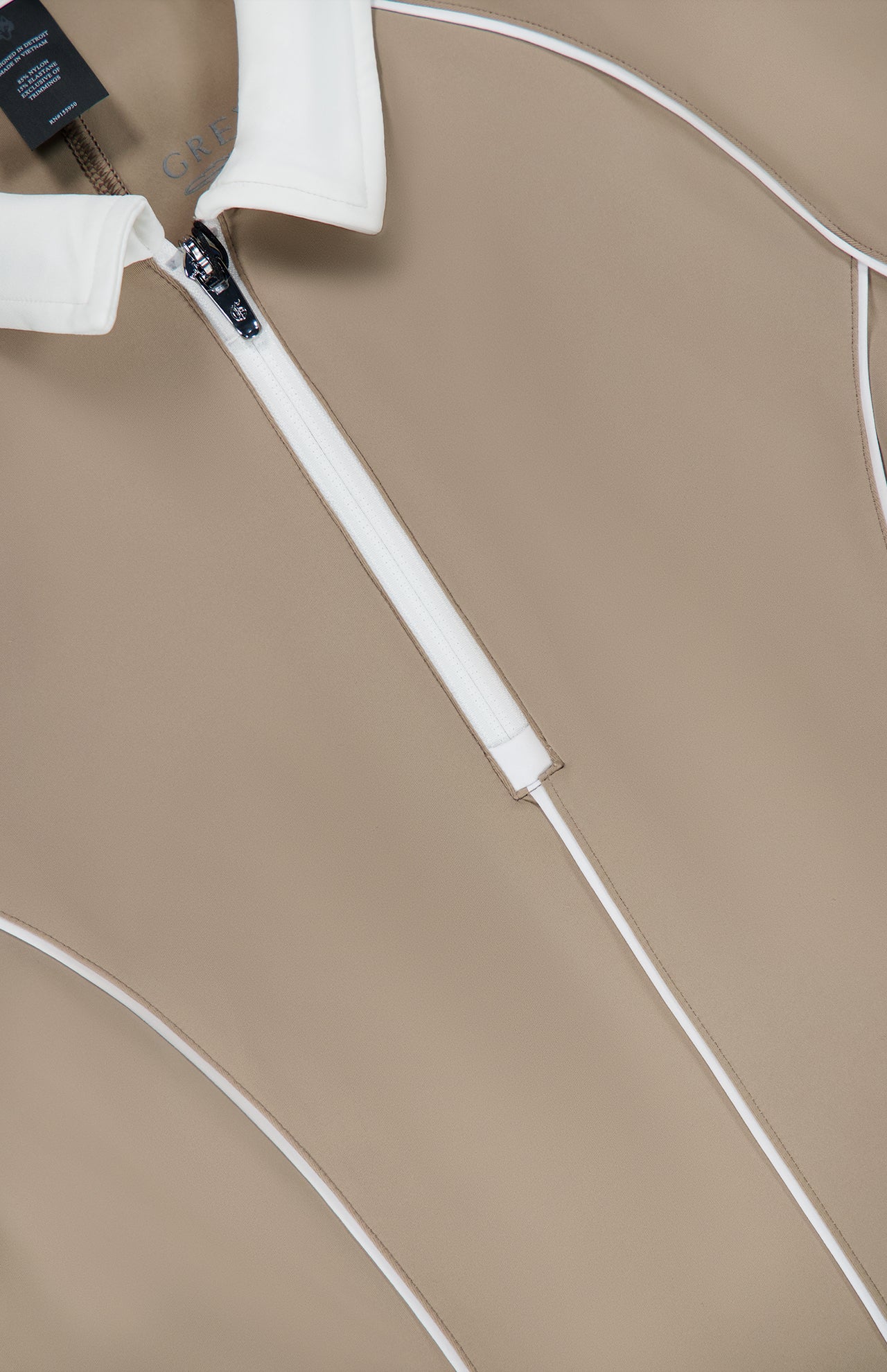 Close-up of a tan Soleil Mini Polo Dress with a white collar, quarter-zip front, and white piping details.