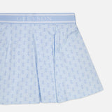 The Wolf Links Phoenix Flare Mini Skirt by GREYSON features a light blue color with a repeating pattern and a wide waistband emblazoned with the brand’s name in white. The fabric has a subtle sheen, and the skirt showcases a flared silhouette with built-in shorts for added comfort.