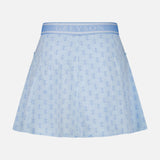 The Wolf Links Phoenix Flare Mini Skirt by GREYSON is a light blue mini skirt showcasing a subtle repeating wolf links monogram pattern. It features built-in shorts for added comfort, a wide waistband with GREYSON branding, and two side pockets, displayed on a plain white background.