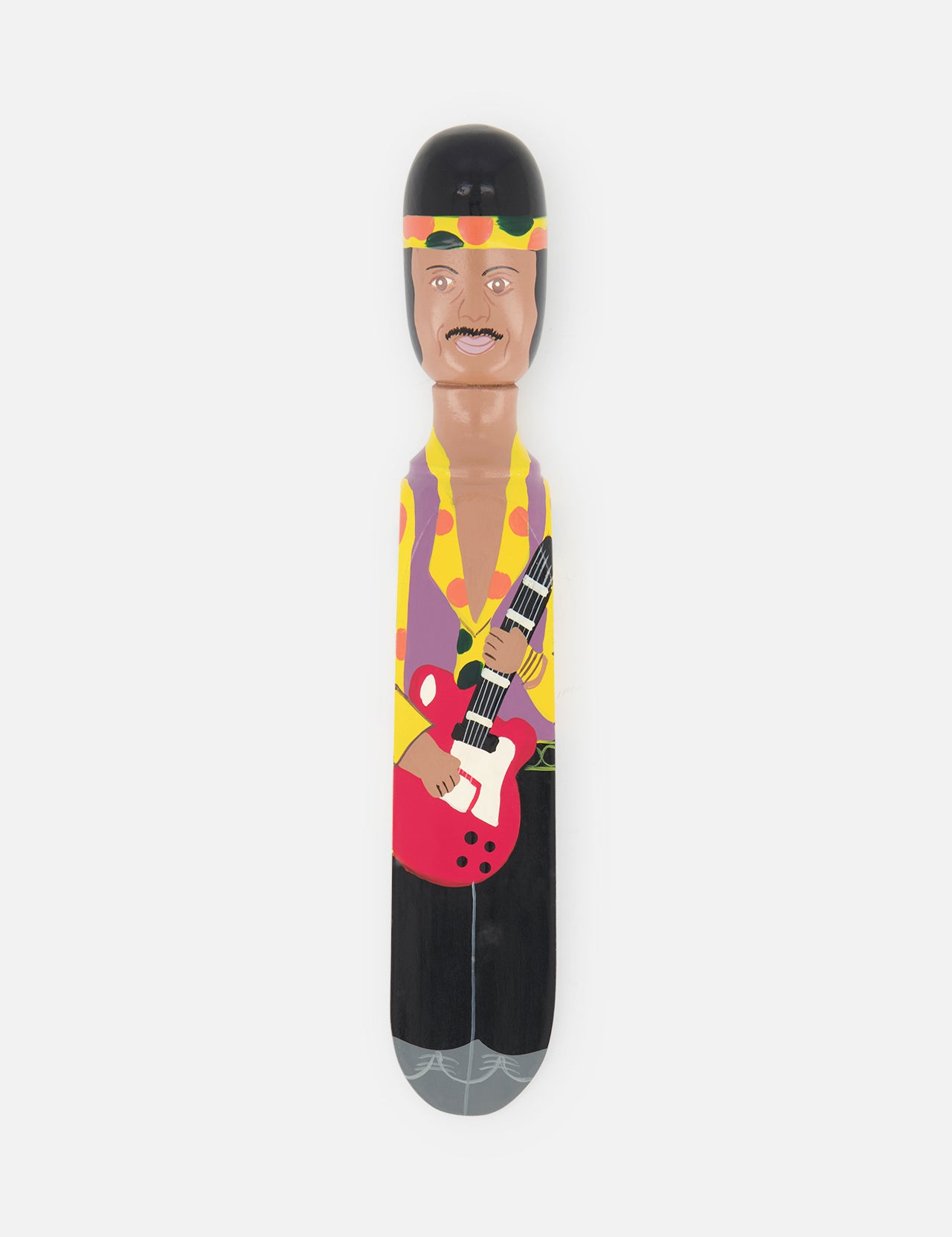 The WEDGIE ‘Hendricks’ Wood Door Stopper is a hand-painted, cartoon-like wooden figurine inspired by Jimi Hendrix, featuring a mustachioed musician in a yellow shirt and headband with a red guitar. Set against a white background.