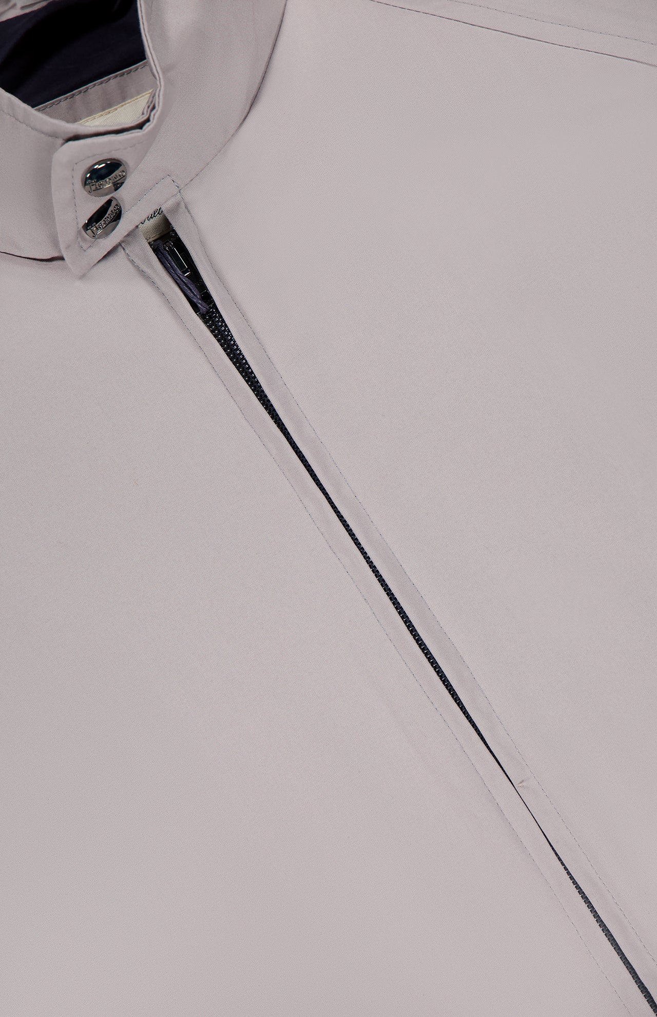 Close-up of the Dean Cotton Bomber Zip Jacket by HERNO in light grey, featuring a high collar, metal snap buttons, and a partial zipper. Its smooth fabric and clean lines make it an ideal choice for men's spring outerwear.