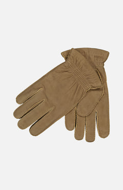 The HESTRA Andre Leather Gloves in light brown chamois leather are shown laid flat on a white background, with one glove overlapping the other and soft wool lining visible at the cuff.