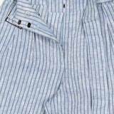 The HEVRON Alina Wide Leg Linen Pant features light blue and white vertical stripes, a high-rise waist with a waistband tab and button closure, shown partially unbuttoned to reveal its interior construction details.
