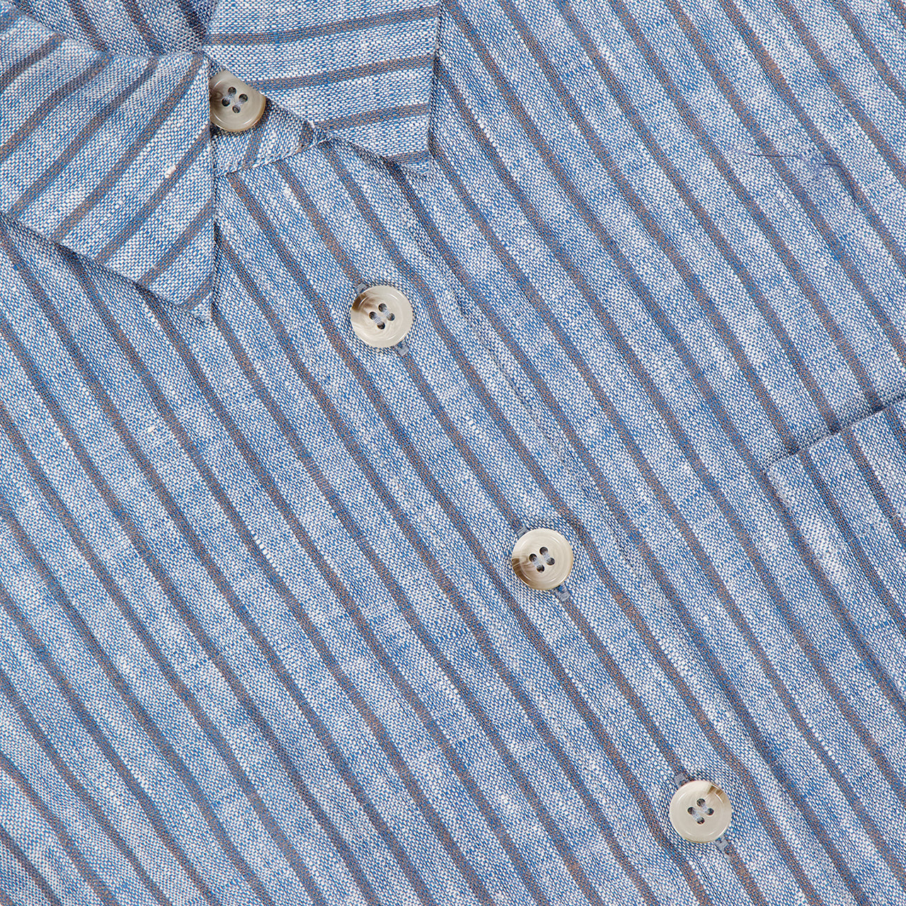 Close-up of the HEVRON Katja Cropped Linen Top, featuring blue and white vertical stripes, five light buttons, two visible pockets, and a textured lightweight linen fabric.