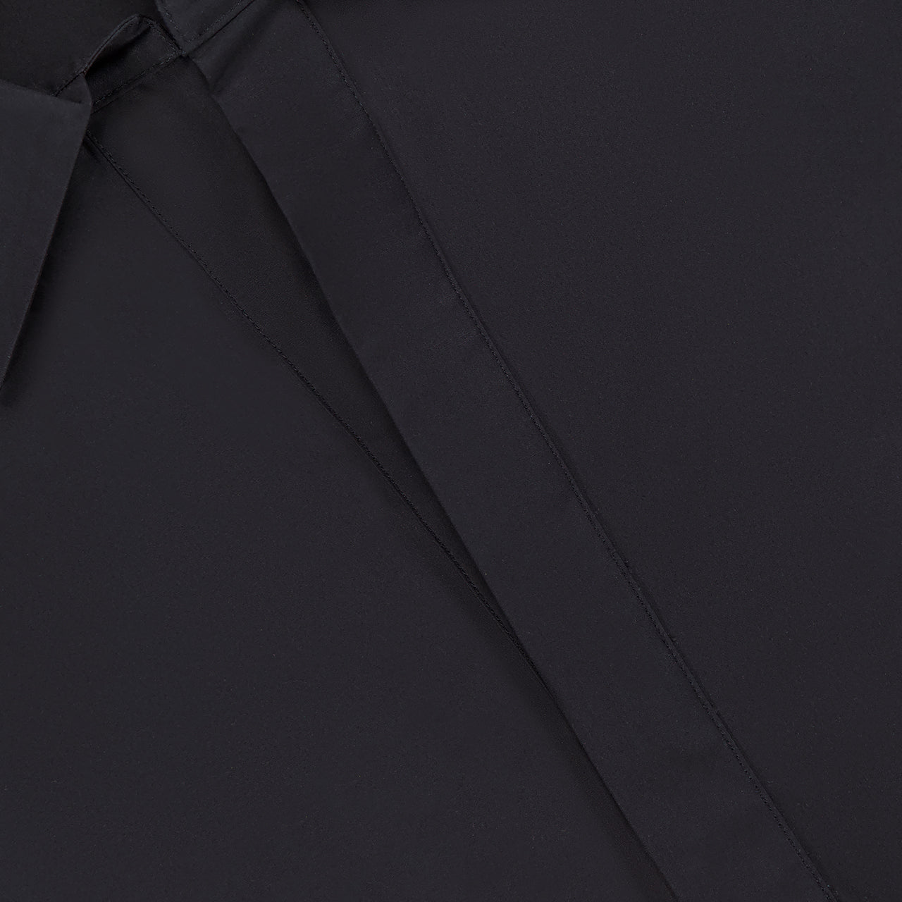 Close-up of the Paola Adjustable Front Top by HEVRON, featuring a hidden button placket, adjustable epaulette detail, and a glimpse of a white label at the neckline.