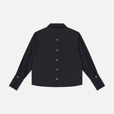 The HEVRON Paola Adjustable Front Top, a black long-sleeve cotton blouse, is shown laid flat on a white background with white center buttons and an adjustable epaulette detail for style.