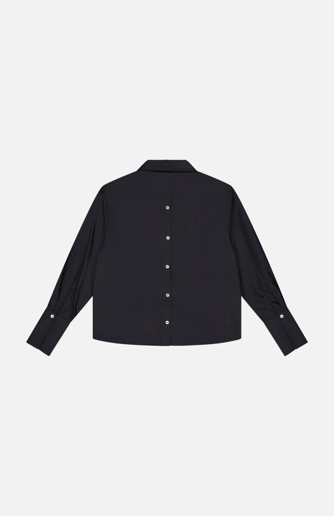 The HEVRON Paola Adjustable Front Top, a black long-sleeve cotton blouse, is shown laid flat on a white background with white center buttons and an adjustable epaulette detail for style.