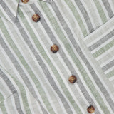 Close-up of the HEVRON Katja Striped Linen Top, featuring vertical green, white, and gray stripes, brown tortoiseshell buttons, a collar, and chest pocket. Light, breathable fabric makes it perfect for summer.