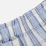 Close-up of HEVRON's Mira Plaid Linen Short, featuring lightweight, breathable linen with a light blue and white plaid pattern, thin dark blue stripes, and an elastic waistband.