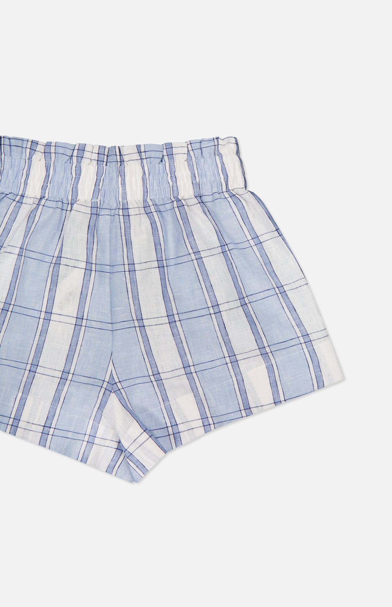 The HEVRON Mira Plaid Linen Short, shown in light blue and white with an elastic waistband and soft linen fabric, is displayed against a plain white background. Only half of the shorts are visible in the image.