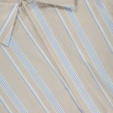 A close-up of the Paola Front Tuck Top by HEVRON shows beige fabric with blue and white vertical stripes, a visible size S tag, the collar, part of the button placket, and a hint of back button detail.