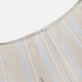 A close-up of the HEVRON Rory Wide Leg Stripe Pant in soft cotton, featuring beige fabric with vertical blue and white stripes, curved seam pleats, and a relaxed wide leg silhouette.