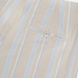 Close-up of the HEVRON Rory Wide Leg Stripe Pant, featuring beige fabric with vertical light blue and white stripes, a back welt pocket with button, and neat stitching.