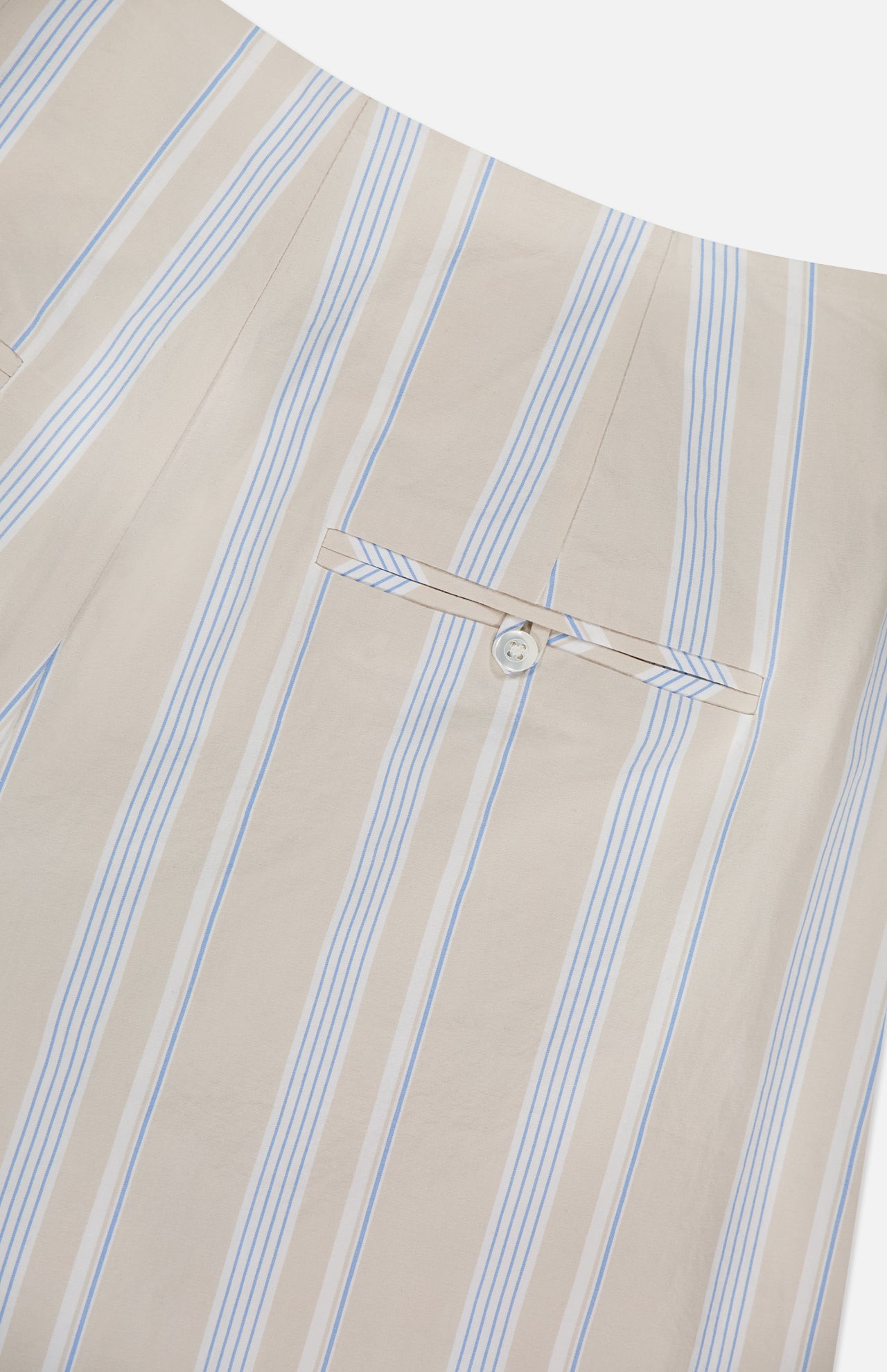 Close-up of the HEVRON Rory Wide Leg Stripe Pant, featuring beige fabric with vertical light blue and white stripes, a back welt pocket with button, and neat stitching.