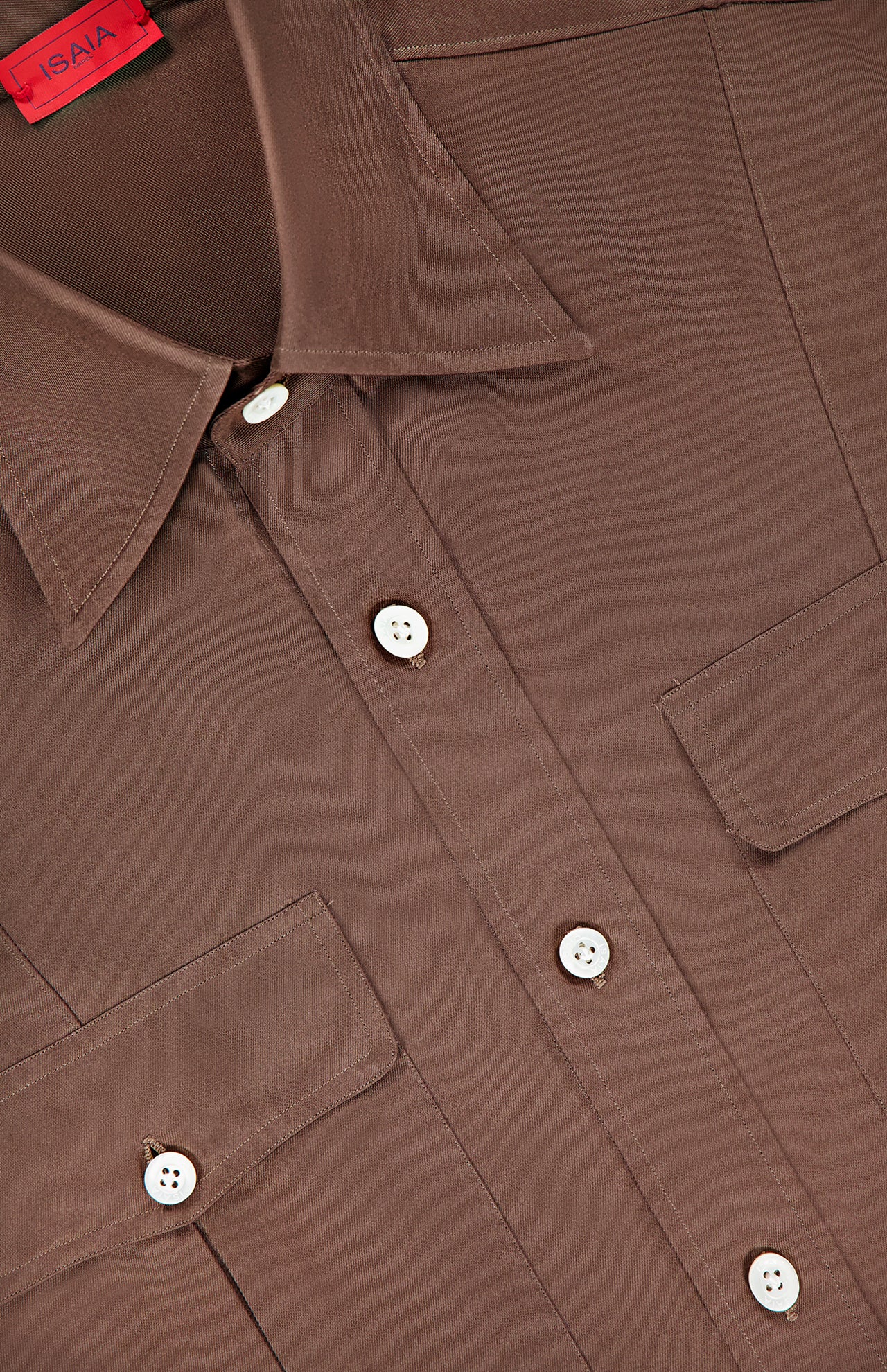Close-up of the ISAIA Camp Long Sleeve Dress Shirt for men in brown, featuring white buttons, two chest pockets with buttoned flaps, and a red tag at the collar.