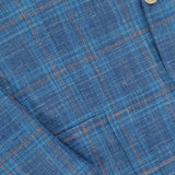 Close-up of the ISAIA Check Light Summer Hopsack Sportcoat, a men's blue plaid blazer with thin brown and light blue lines, showing fabric texture, pocket, lapel, and button details.