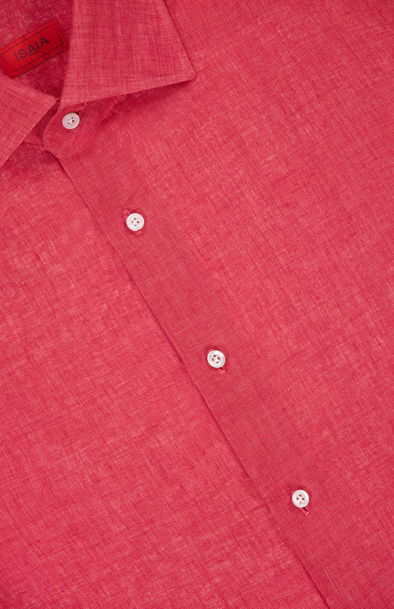 A close-up of a red Textured Linen Dress Shirt by ISAIA features white buttons and a visible collar. The inside label displays the ISAIA brand, emphasizing this Italian-made shirt’s refined craftsmanship.